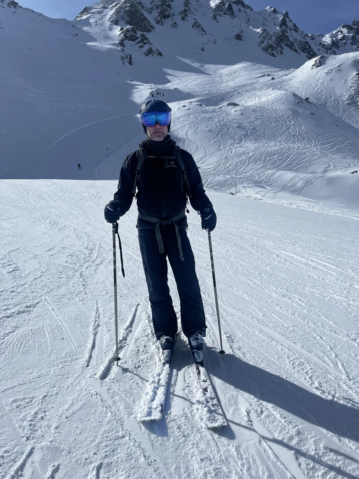 Robert Gerhards mit Ski, Helm und Skibrille vor einem verschneiten Berghang